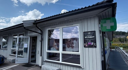 Inngang til M Beauty ved Skedsmokorset, Akershus, NO, med reklameplakater i vinduene.