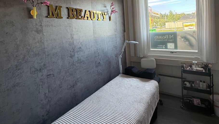 Koselig behandlingsrom ved M Beauty i Skedsmokorset, Akershus, NO, med komfortabel benk og naturlig lys.