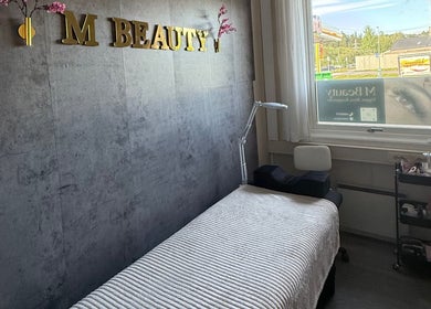 Koselig behandlingsrom ved M Beauty i Skedsmokorset, Akershus, NO, med komfortabel benk og naturlig lys.