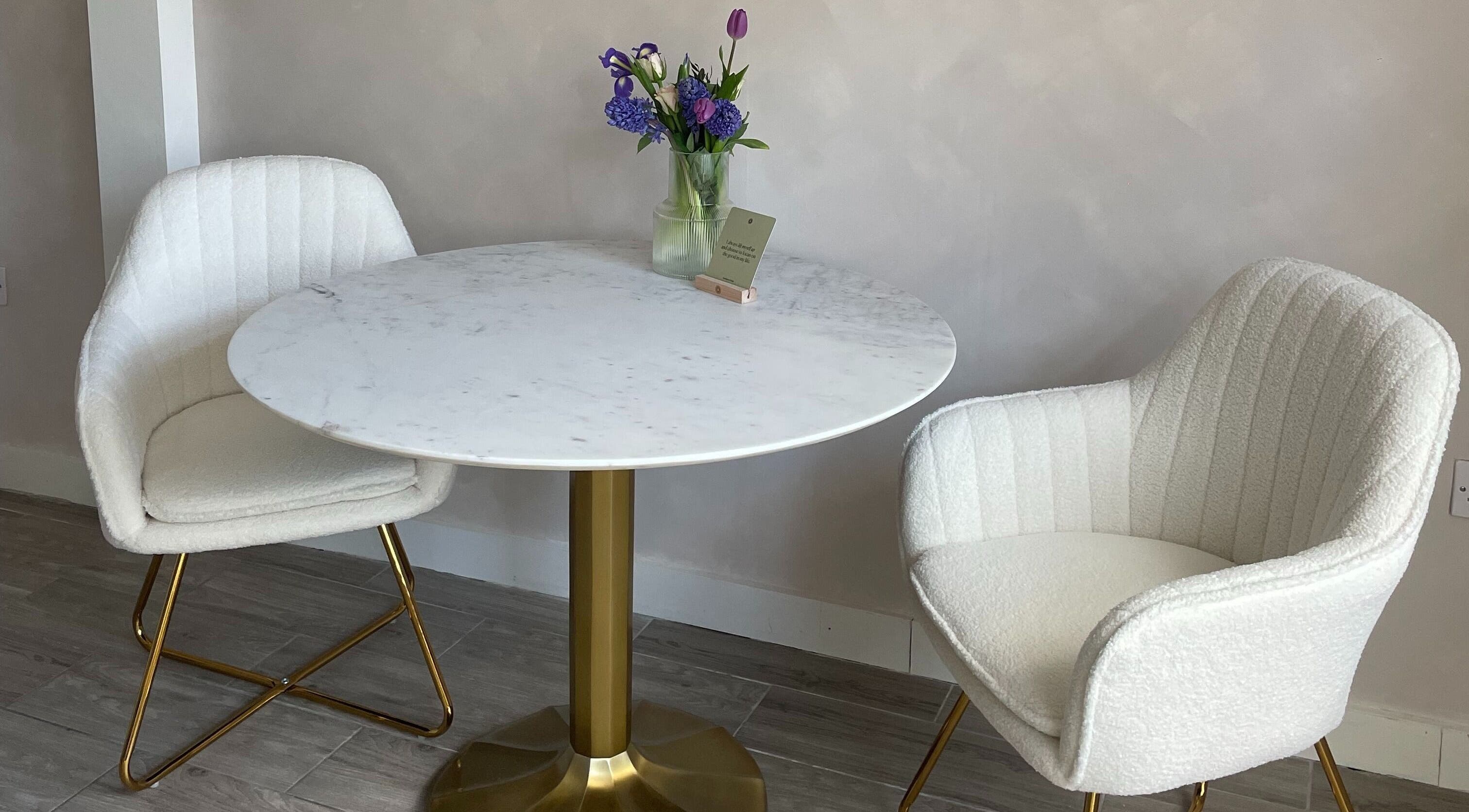 Elegant seating area at The Skin Studio Cirencester, Cirencester, England, GB with a marble table and plush chairs.