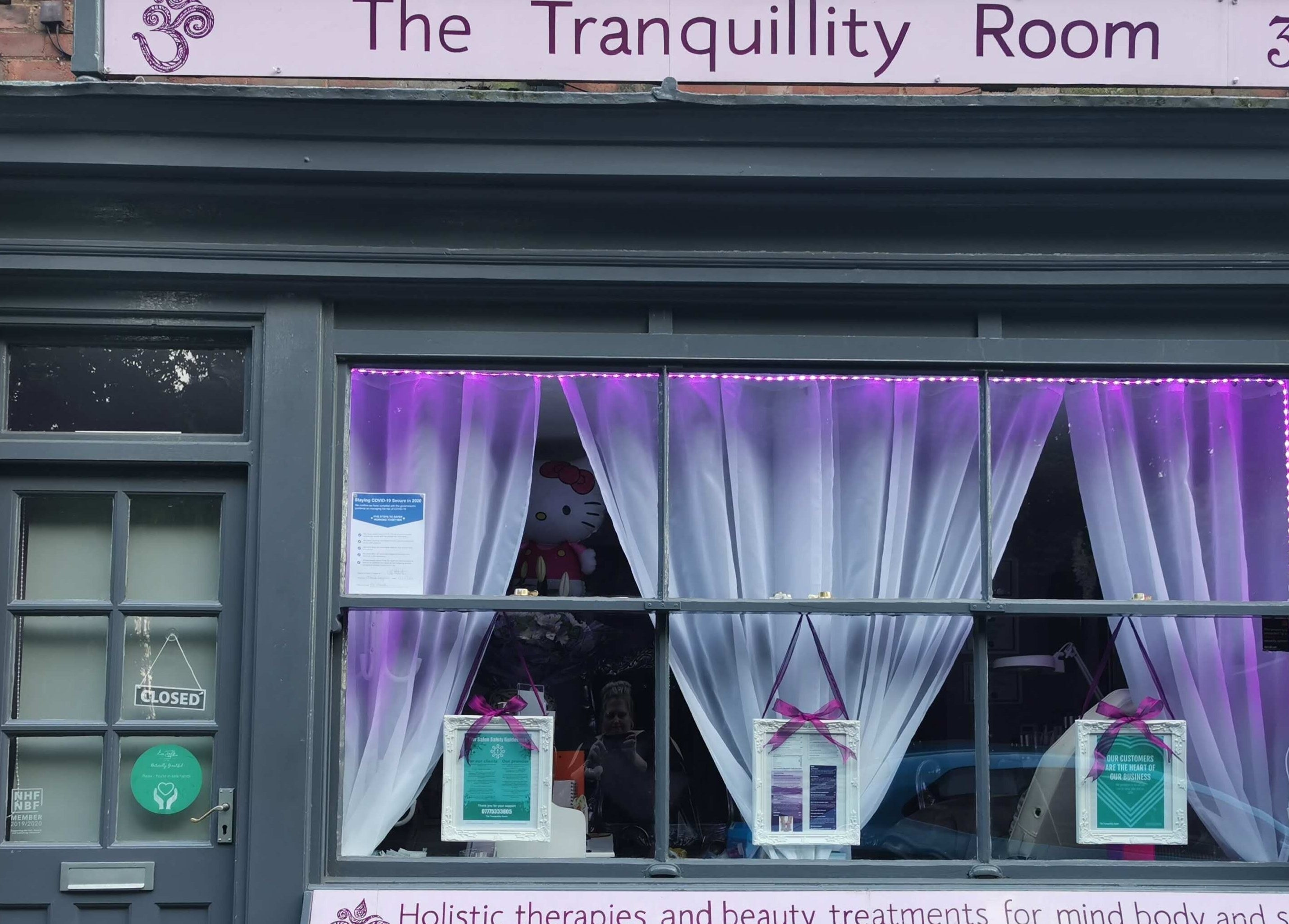Exterior of The Tranquillity Room in Woodhall Spa, England, with purple-lit curtains and closed sign.