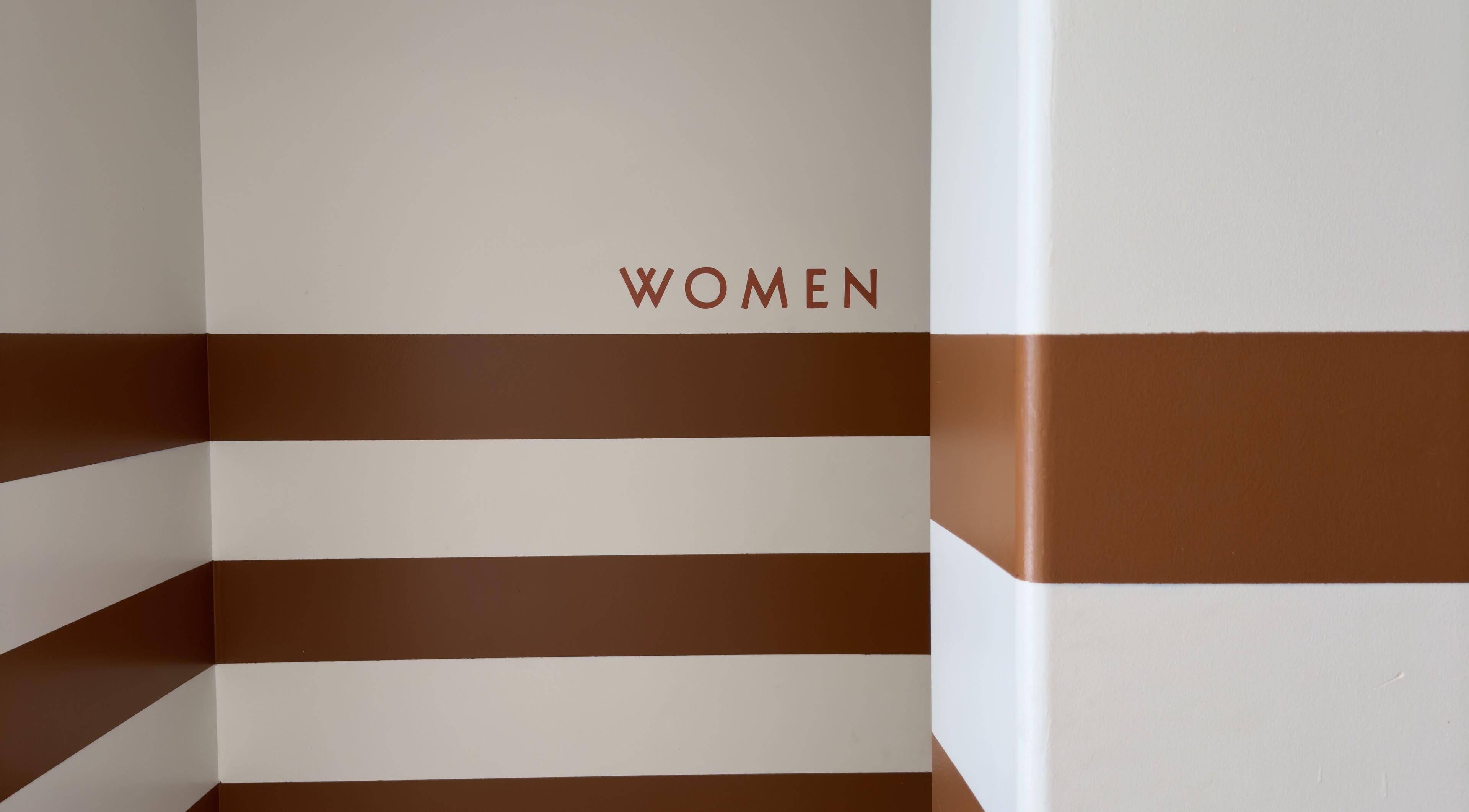 Mur rayé brun et blanc à LASH LOUNGE, Cenon, Nouvelle-aquitaine, FR avec inscription 'WOMEN'.