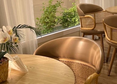 Elegant seating area at Alzaina salon, Umm Salal Muhammed, featuring wicker chairs and a floral arrangement.