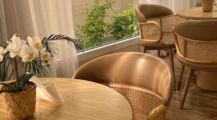 Elegant seating area at Alzaina salon, Umm Salal Muhammed, featuring wicker chairs and a floral arrangement.