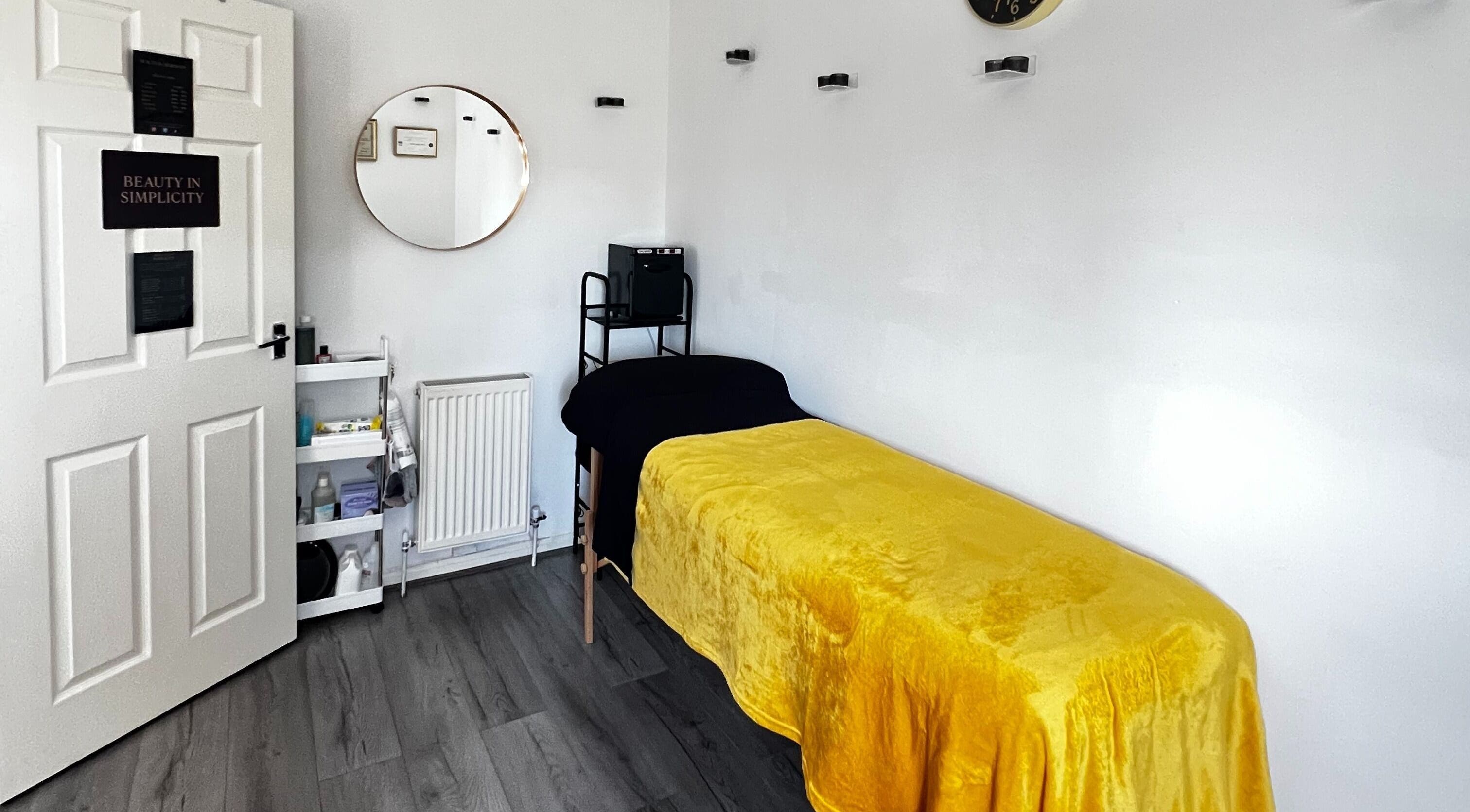 Relaxing treatment room at Beauty In Simplicity, Warrington, England, with a yellow cover on a massage bed.