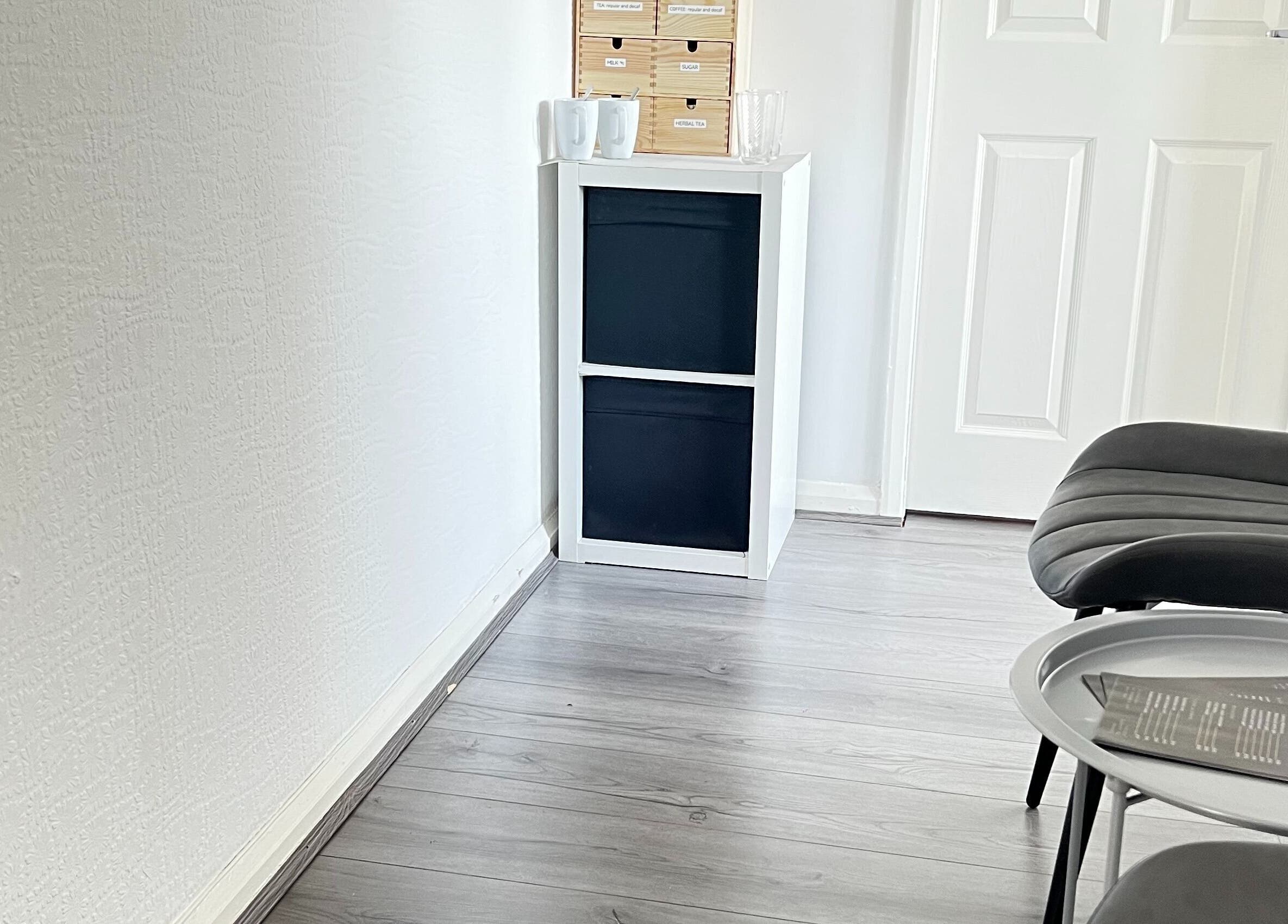 Modern waiting area at Beauty In Simplicity, Warrington, England, GB with sleek black chair and white shelf.