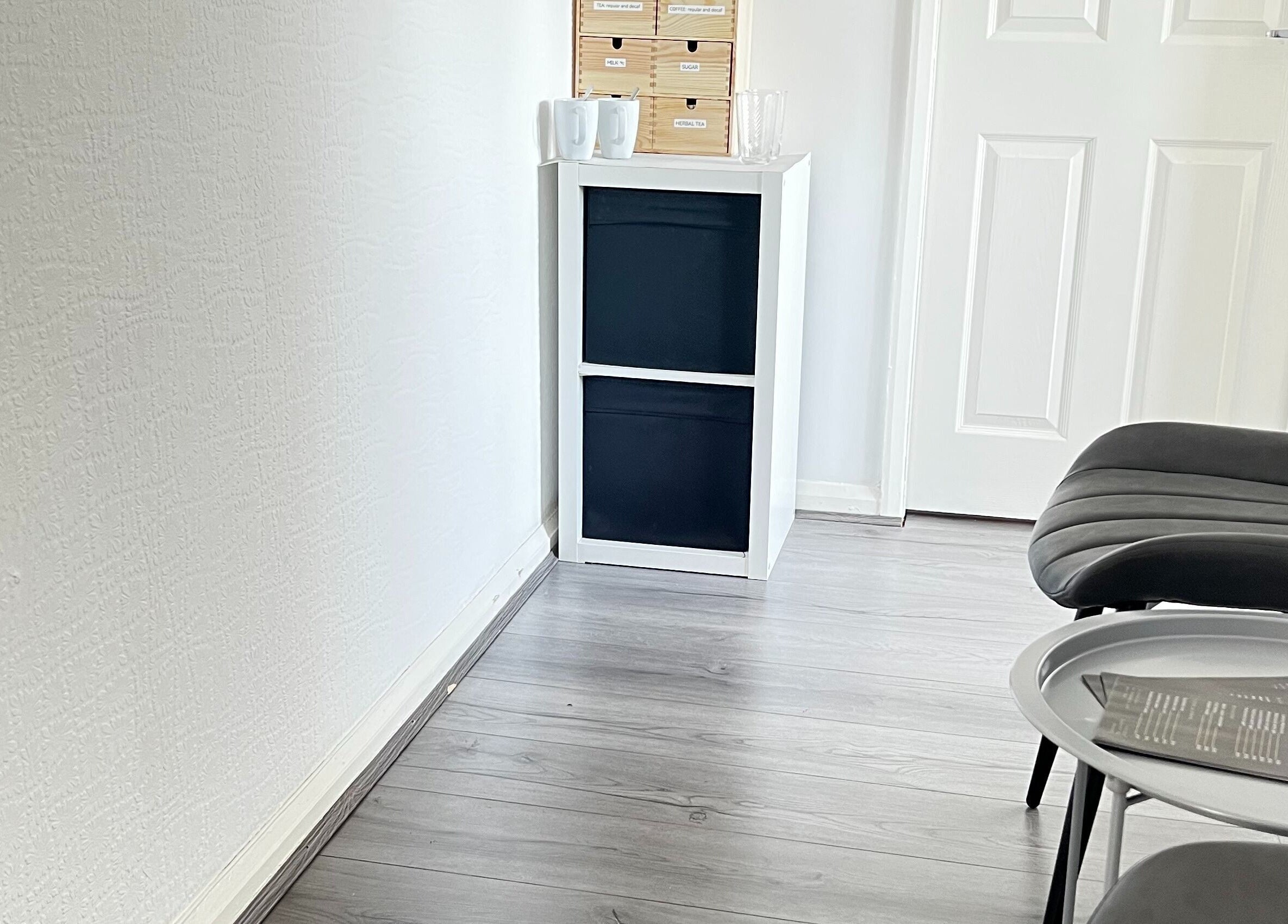 Modern waiting area at Beauty In Simplicity, Warrington, England, GB with sleek black chair and white shelf.