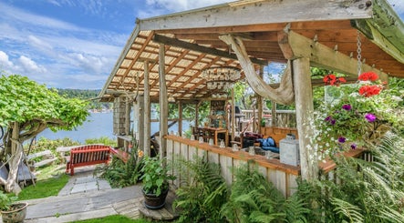 Outdoor rustic patio at Shinrin-Yoku Spa with lush plants, Bamfield, British Columbia, CA.