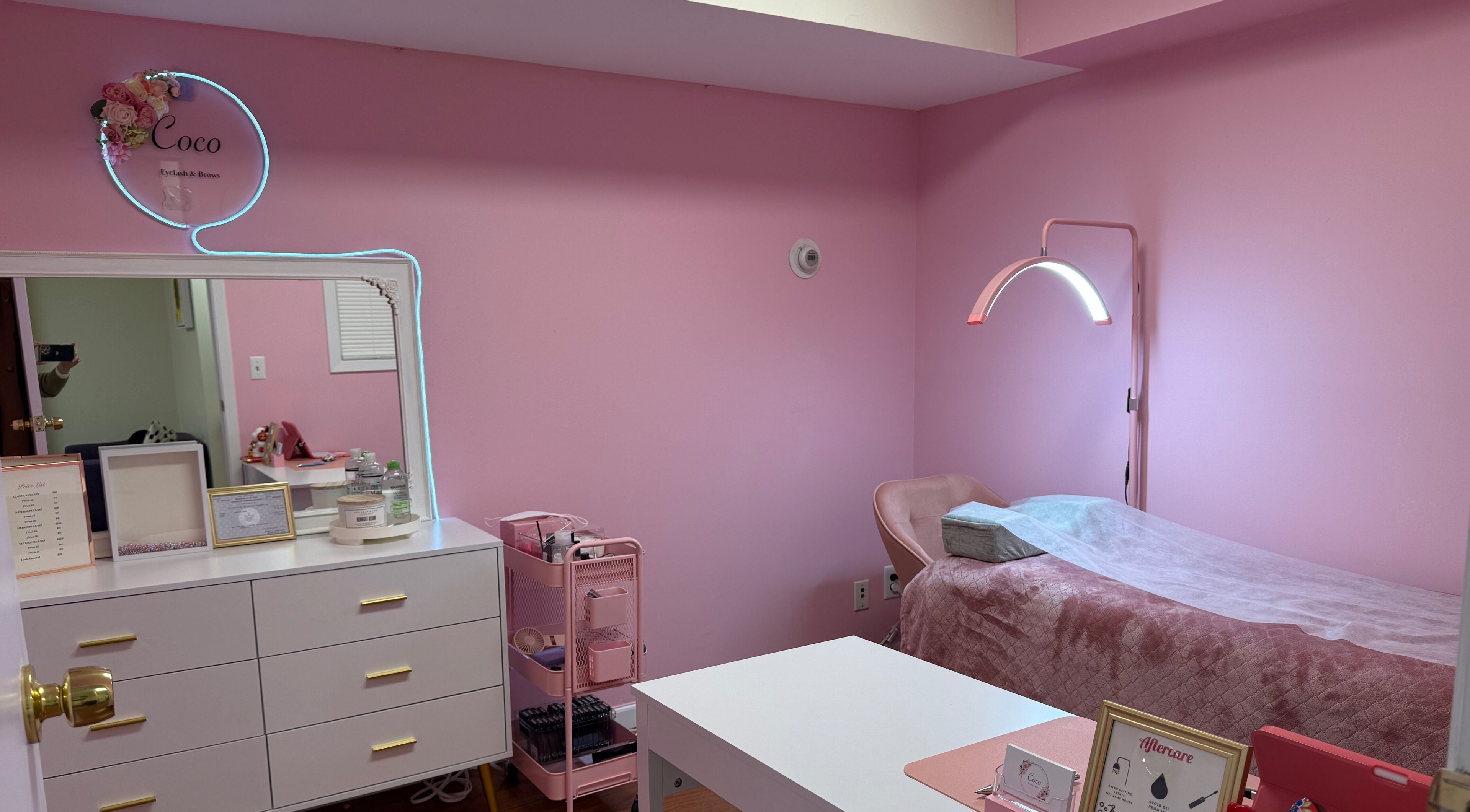 Interior of Coco Eyelash & Brows.Llc, New York, with a pink theme, treatment bed, and decor.