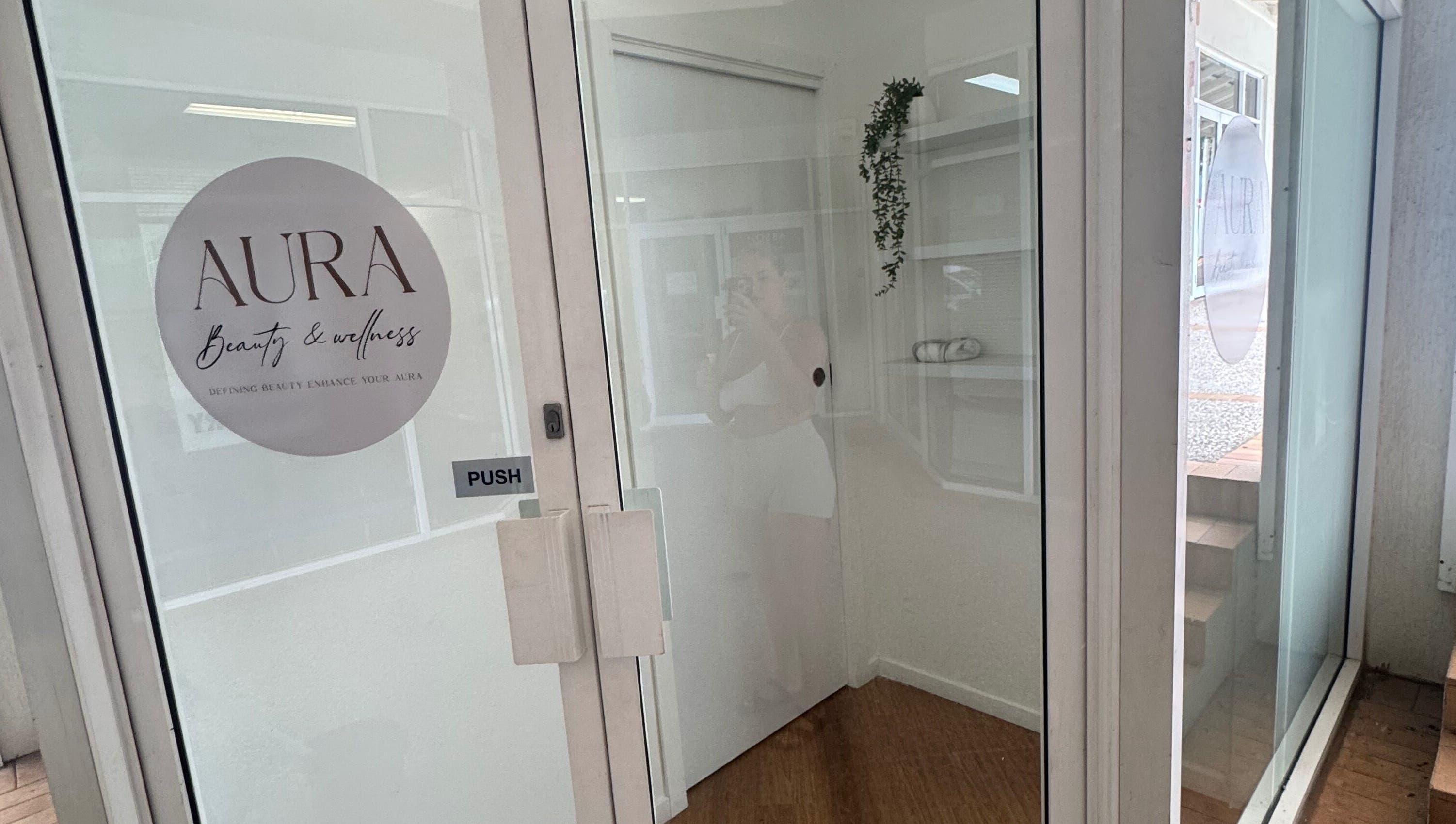 Entrance to AURA Beauty and Wellness in Nerang, Queensland, AU with glass door and logo.