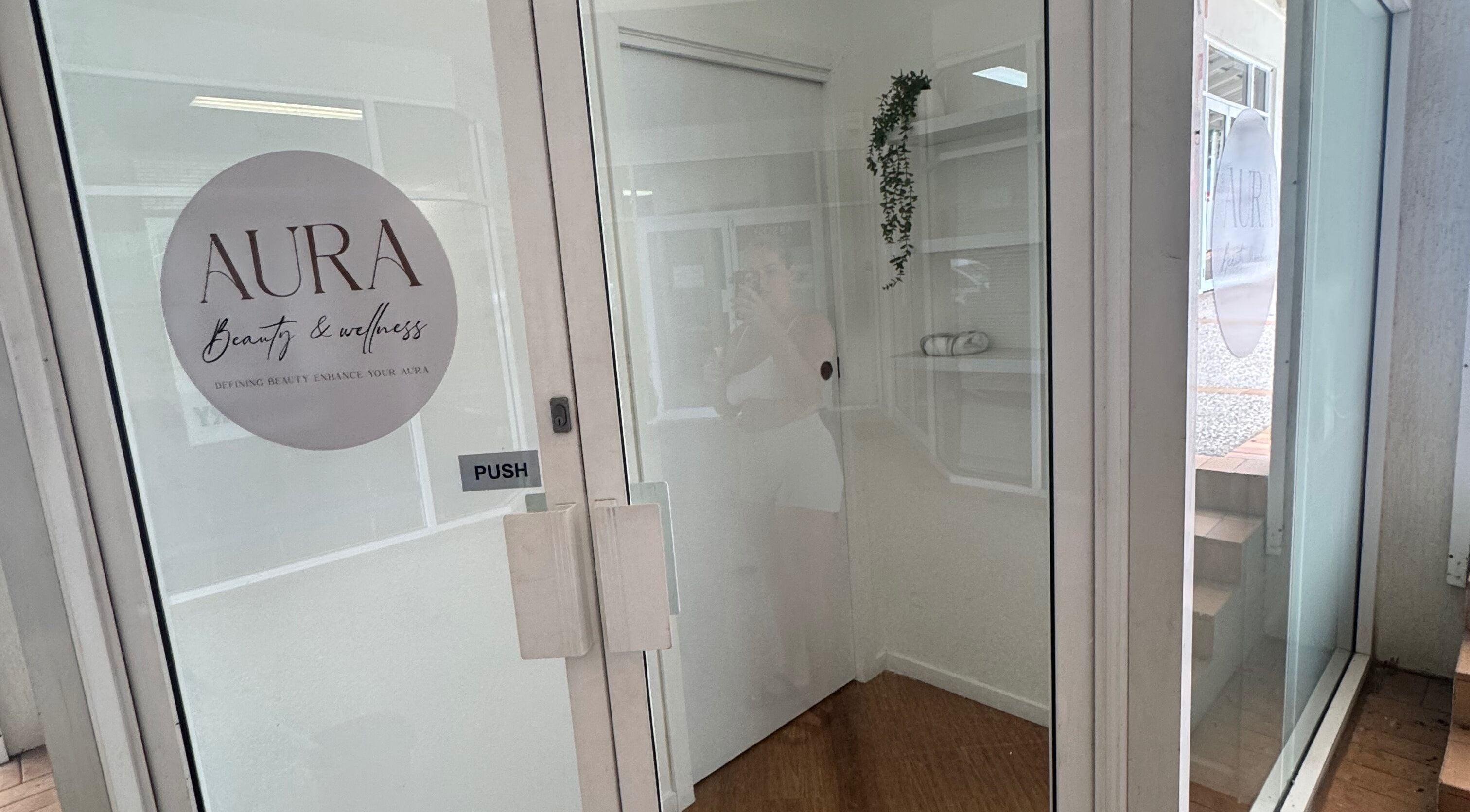 Entrance to AURA Beauty and Wellness in Nerang, Queensland, AU with glass door and logo.