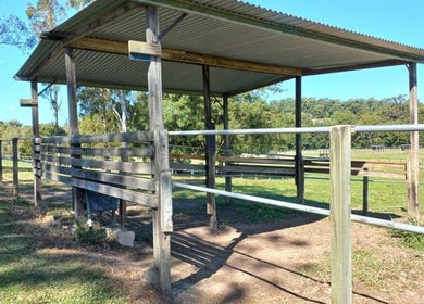 Outdoor rustic pavilion at Elara Lodge, Yandina Creek, Queensland, AU, surrounded by lush greenery.