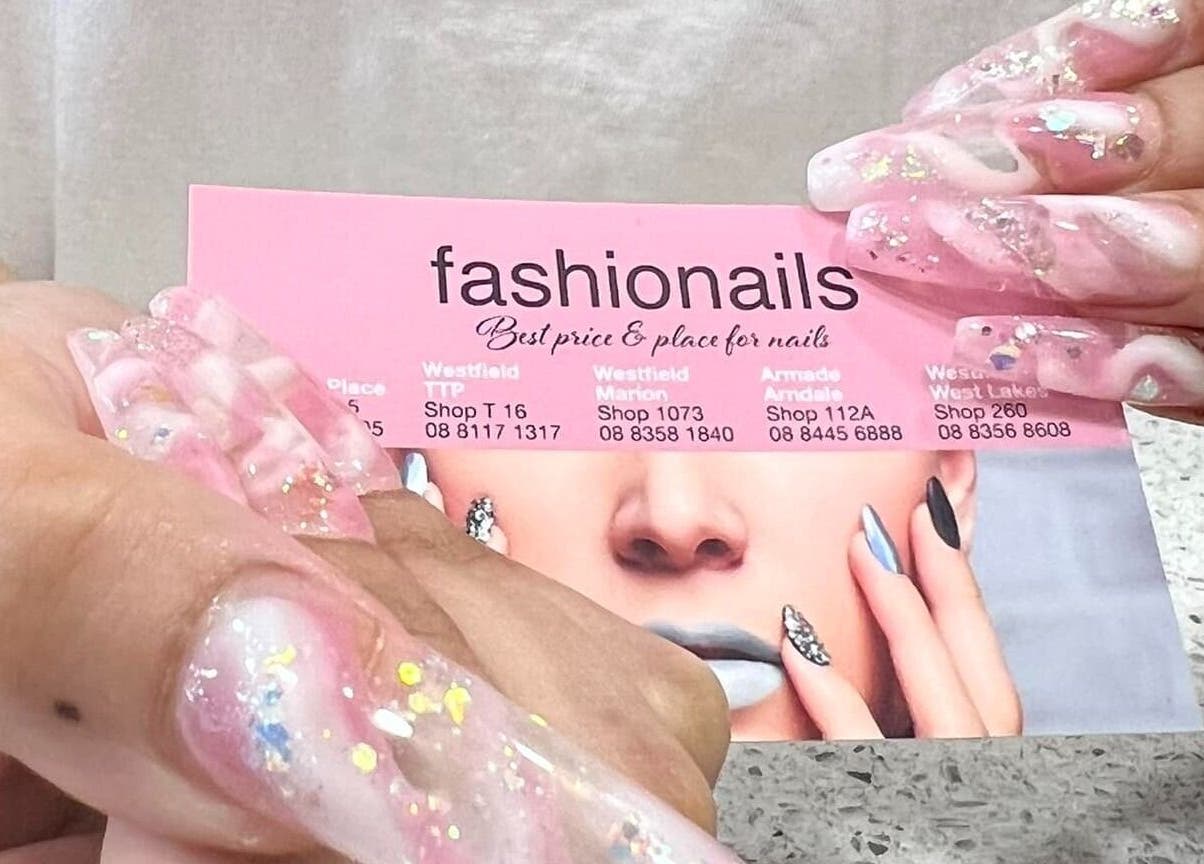 Close-up of glittery pink nails holding Fashion Nails Rundle Place card in Adelaide, South Australia, AU.