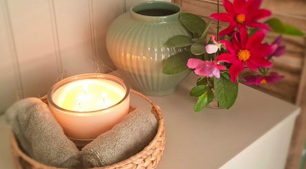 Relaxing candlelit setup at The Holistic Healing Hut, Gweek, England, GB with vibrant flowers and soft towels.