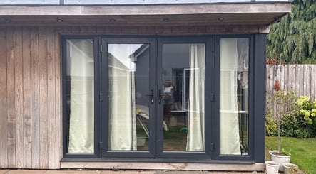 Glass doors at No.6 Beauty Lounge in Winterbourne, England, GB, overlooking a serene garden setting.