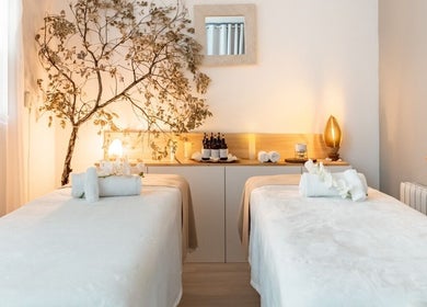 Sala de masaje tranquila en Moon Relax Spa, Barcelona, Catalunya, ES, decorada con velas y toallas blancas.