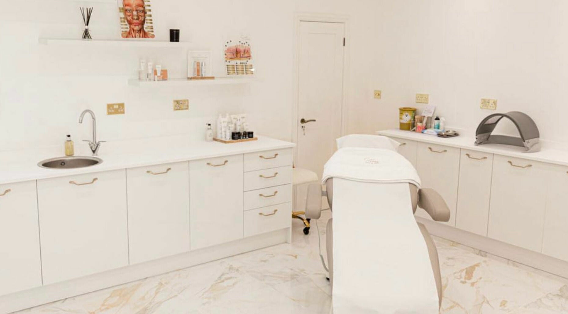 Spa room at Sarah Lynne Aesthetics, Porthmadog, Wales, GB with white cabinets and a treatment bed.