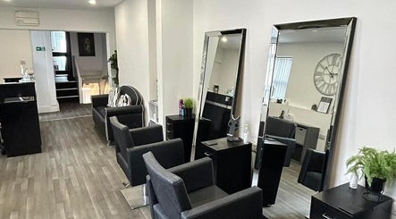Modern salon interior at Glammedbyamelia in Plymouth, England, GB, showcasing sleek black chairs and large mirrors.