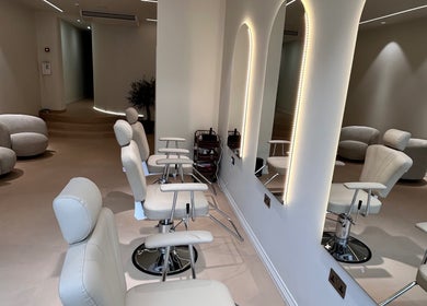 Chic interior of GB BROWS in London, England, GB with modern white chairs and illuminated mirrors.