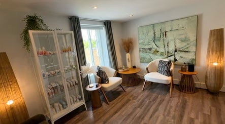 Intérieur élégant du salon DĒLUMI à Mirabel, Canada, CA avec fauteuils blancs et décoration moderne.