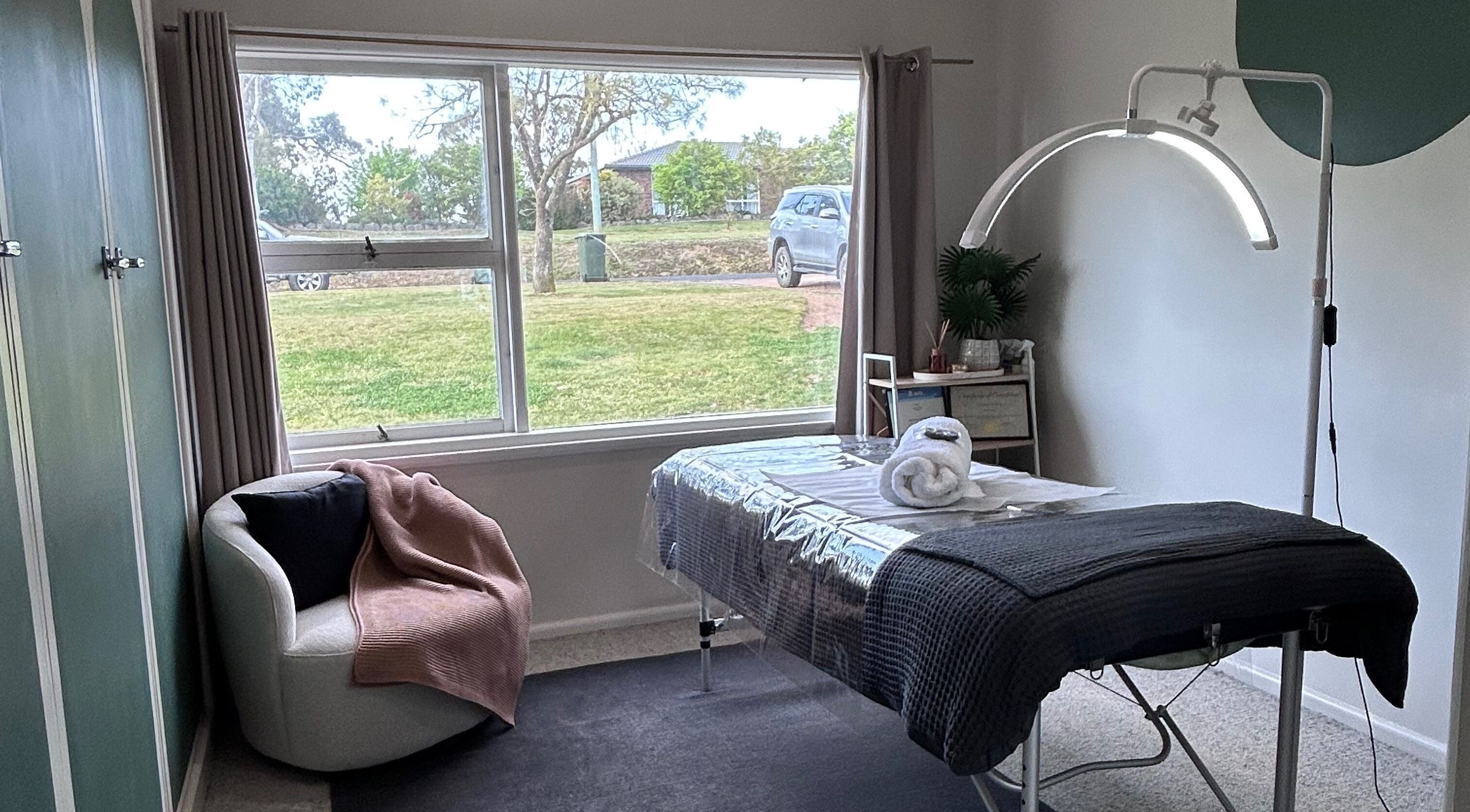 Serene massage room at Wild River Beauty, Walcha, New South Wales, AU with a cozy chair and treatment bed.