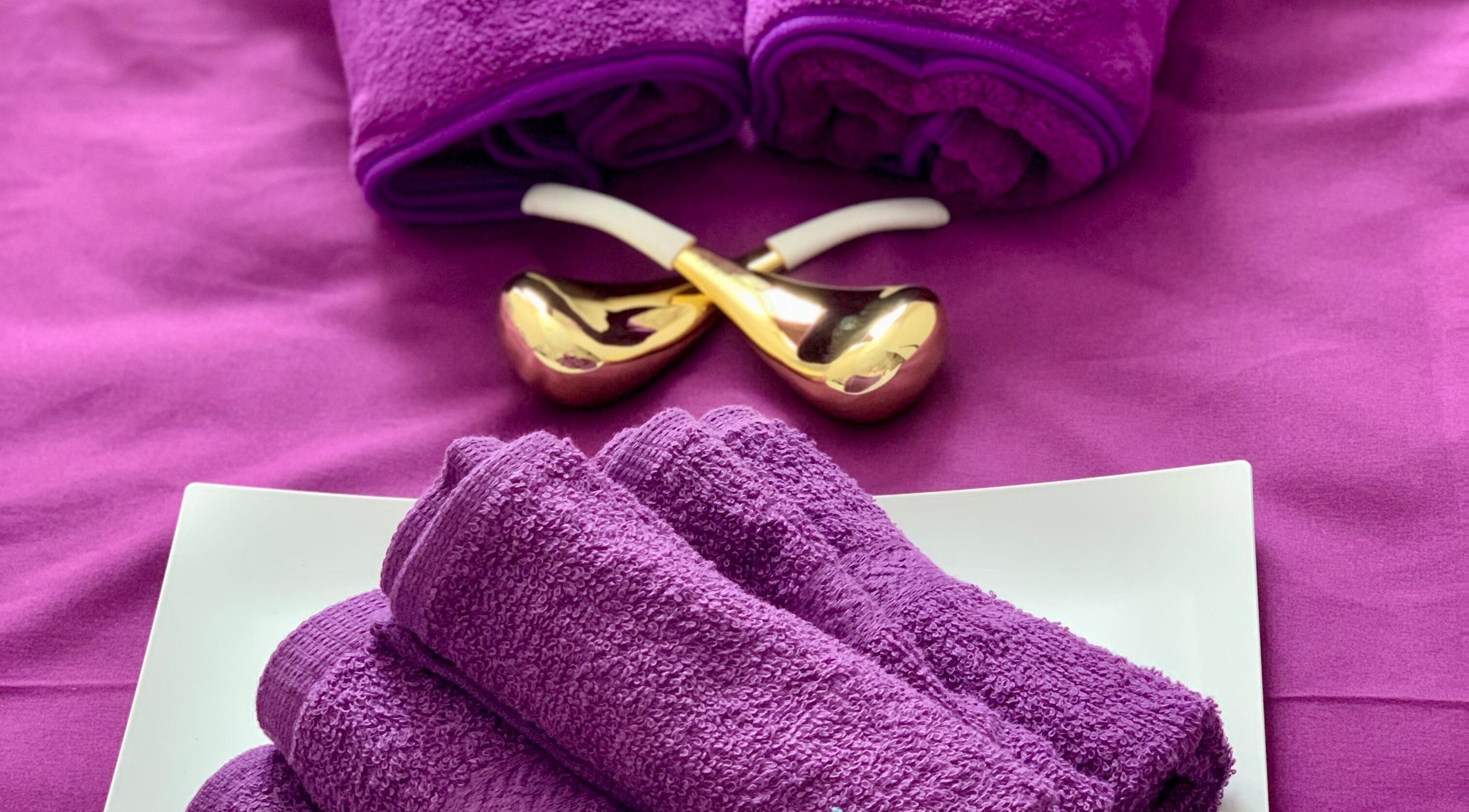 Plush purple towels and gold massage tools at Ur Beauty Oasis, Royal Tunbridge Wells, England, GB.