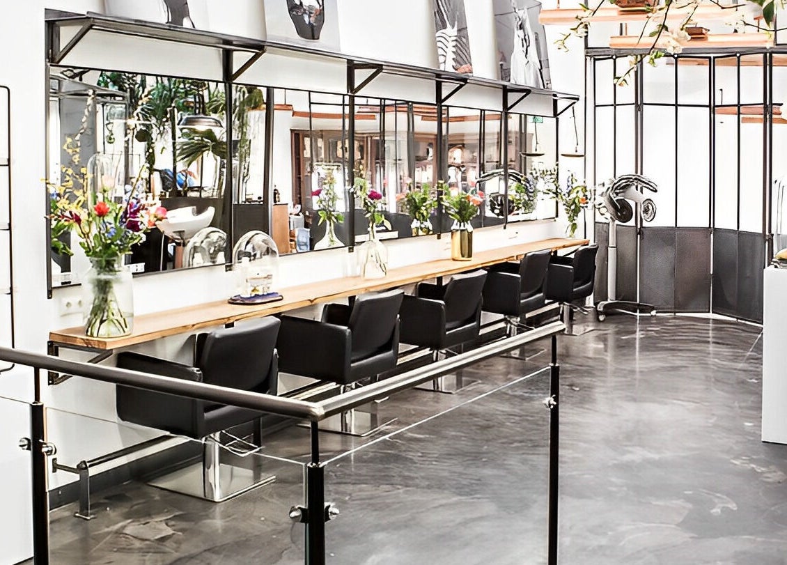 Elegant interior of Mogeen salon in Amsterdam, Noord-Holland, NL with modern chairs and floral decor.