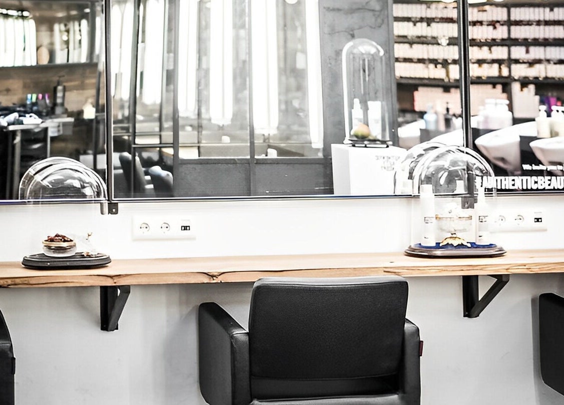 Modern hair styling station at Mogeen, Amsterdam, Noord-Holland, NL, featuring sleek black chairs and mirrors.