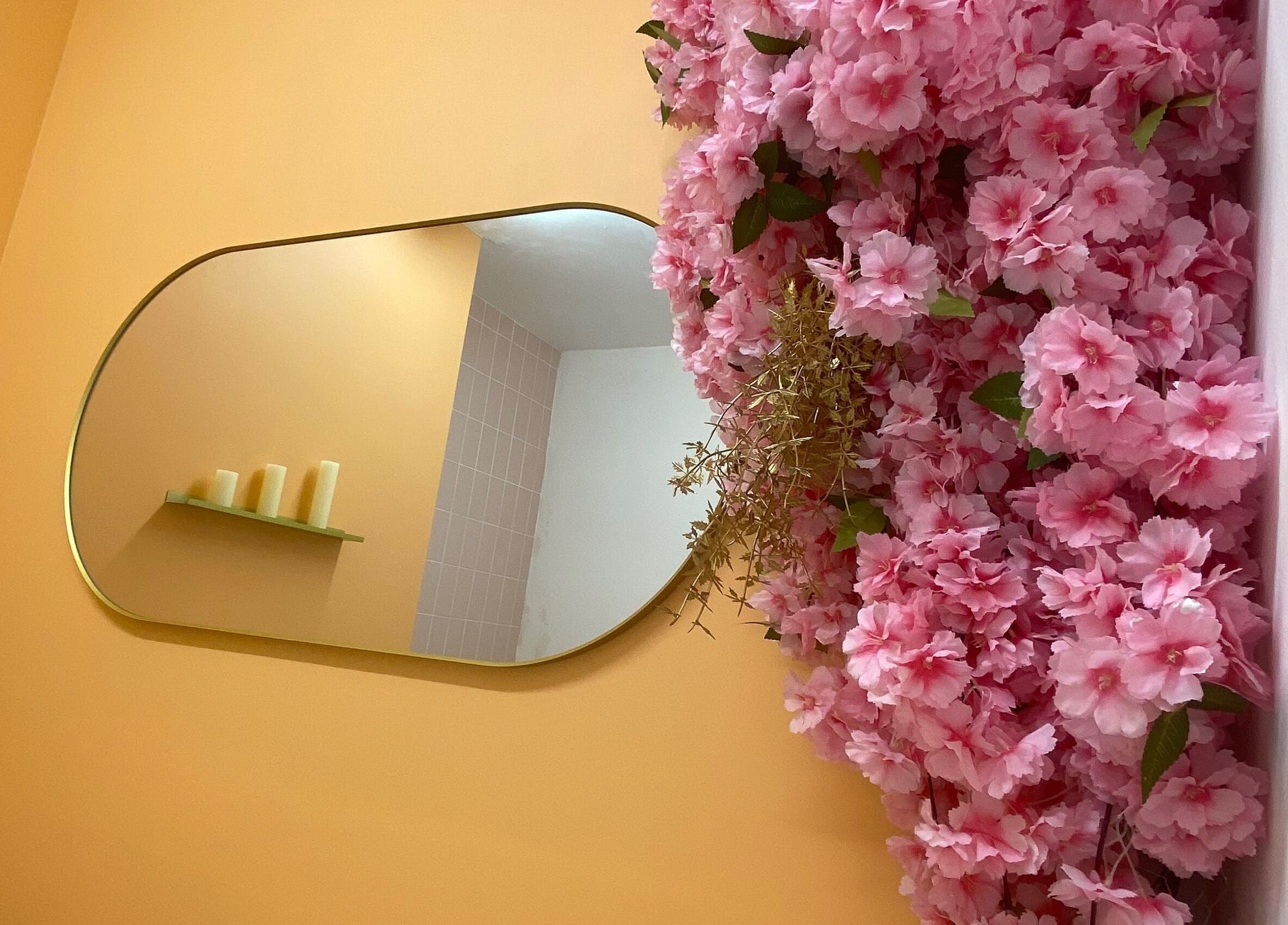 Elegant interior of Peaches Beauty Studio, Nottingham with pink blooms cascading by a stylish mirror.