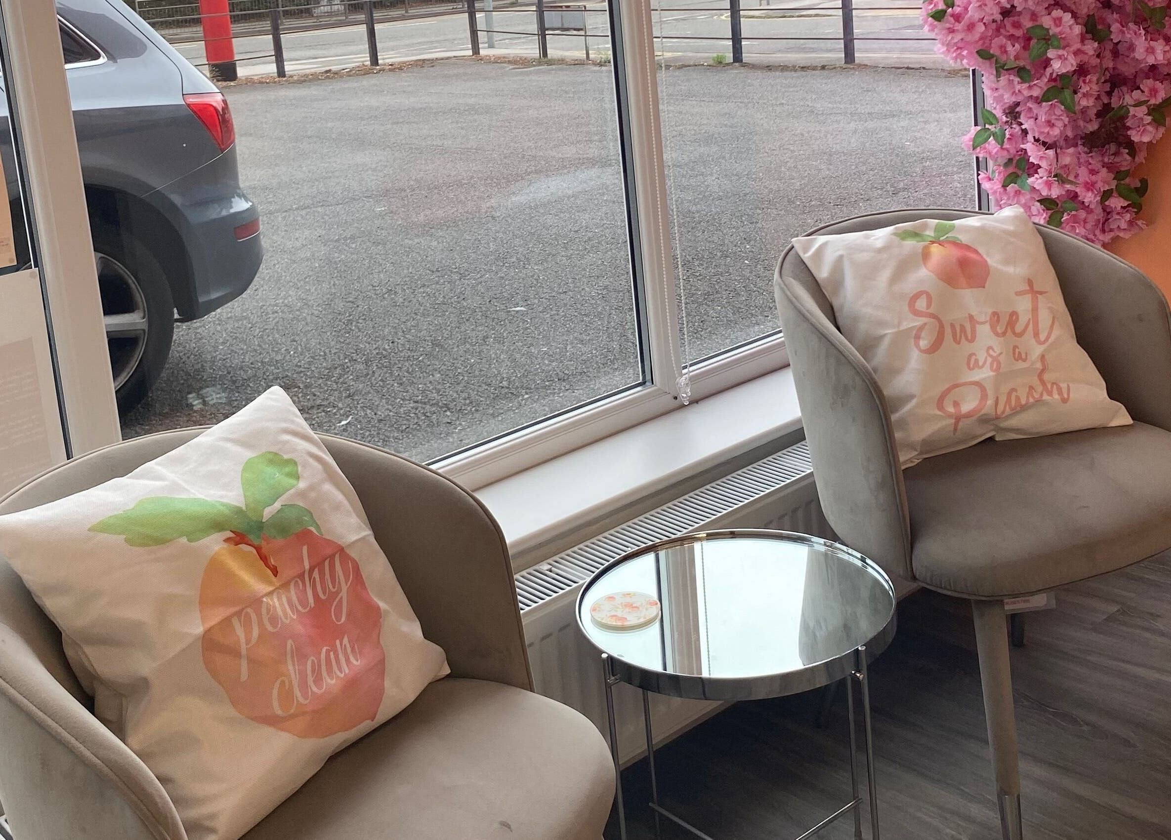 Cozy seating area at Peaches Beauty Studio, Nottingham, England, GB with peach-themed pillows.