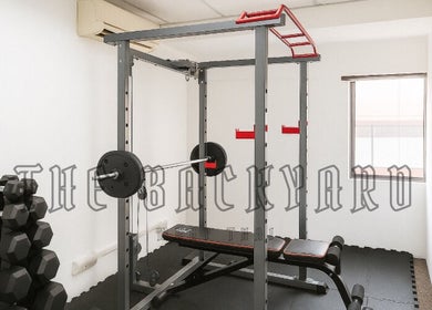 Gym setup at The Backyard Muay Thai in Kuala Lumpur, featuring weights and a workout bench.