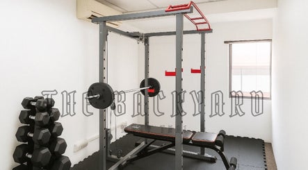 Gym setup at The Backyard Muay Thai in Kuala Lumpur, featuring weights and a workout bench.