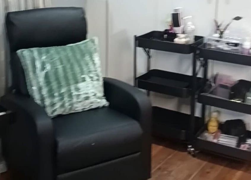 Cozy chair with green pillow at Lanie's Touch, Benoni, Gauteng, ZA, against makeup carts.