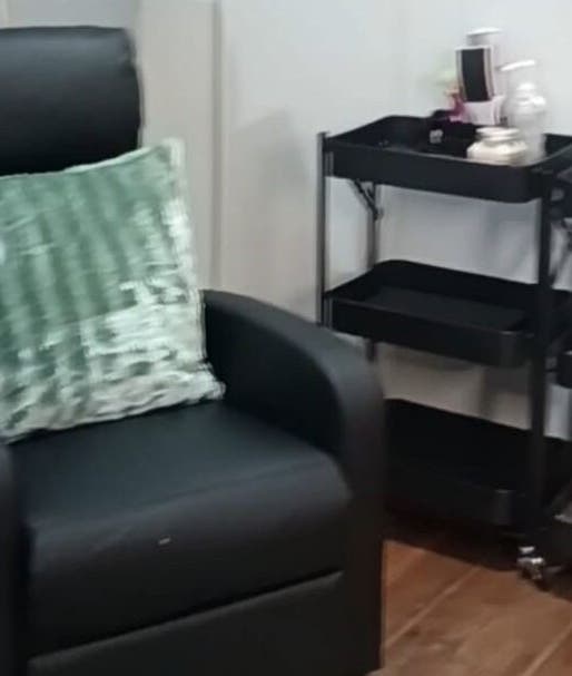 Cozy chair with green pillow at Lanie's Touch, Benoni, Gauteng, ZA, against makeup carts.