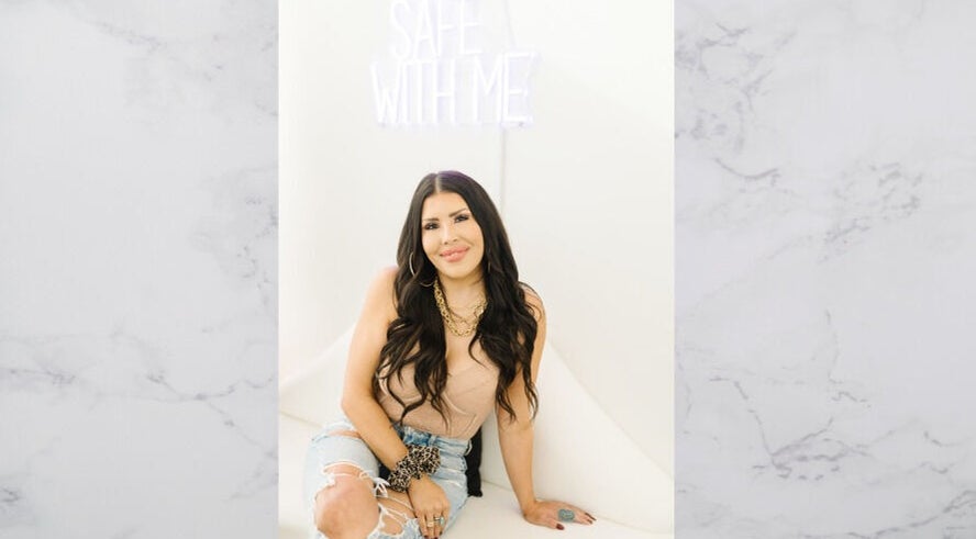 Woman smiling at The OG Brazilianaire Studio, Spanish Fork, Utah, US, under 'Safe With Me' sign.