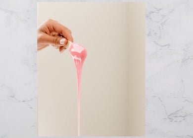 Hand holding pink wax at The OG Brazilianaire Studio in Spanish Fork, Utah, US, showcasing waxing services.