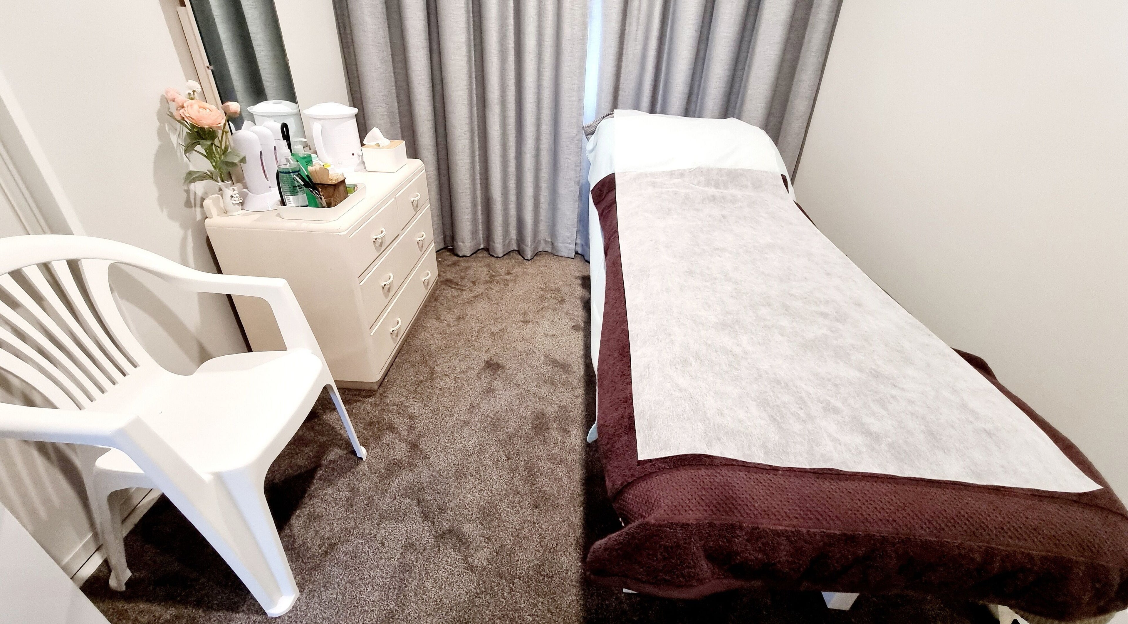 Cozy JDBeauty treatment room at Pegasus, Canterbury Region, NZ with bed, chair, and dresser.