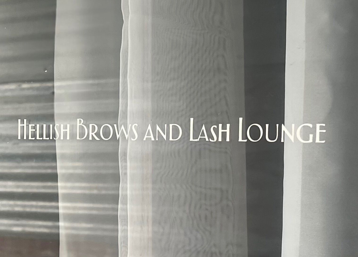 Entrance signage of Hellish Brows and Lash Lounge, Forest Hill, Queensland, AU on glass door.