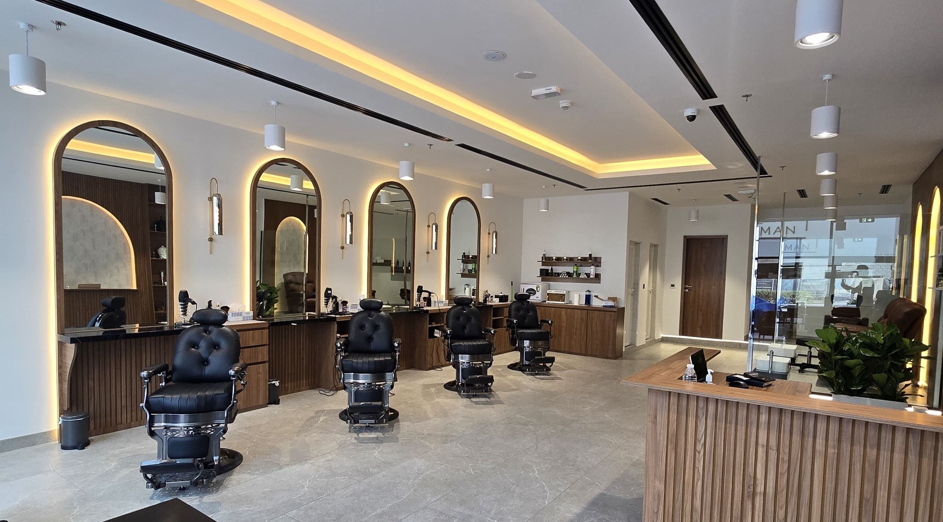 Interior of The Good Man salon in Dubai, Dubai, AE with sleek black chairs and warm lighting.
