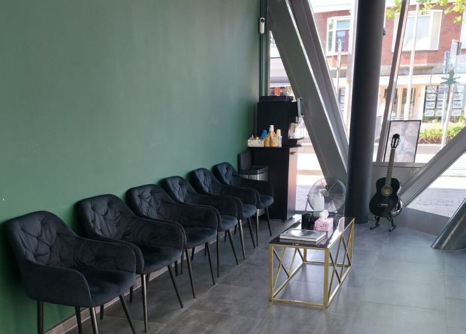 Moderne wachtkamer bij Barbershop Milaan, Pijnacker, Zuid-holland, NL met comfortabele stoelen en gitaar.