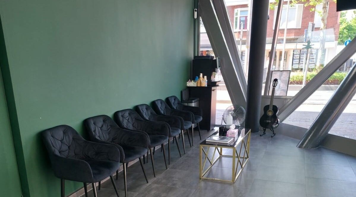 Moderne wachtkamer bij Barbershop Milaan, Pijnacker, Zuid-holland, NL met comfortabele stoelen en gitaar.