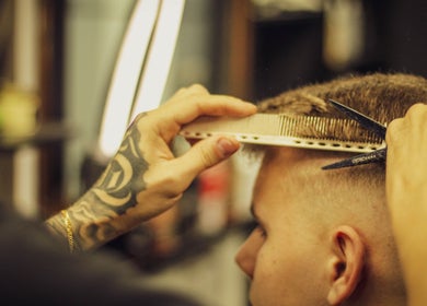 Haircut in progress at Fade O Clock, Dublin, County Dublin, IE. Close-up of stylist using scissors and comb.