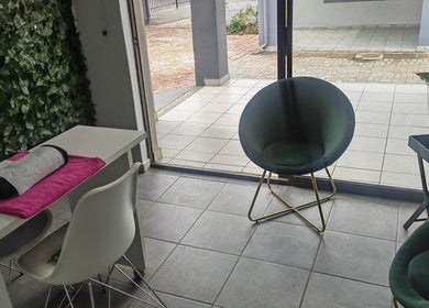 Chic seating and manicure setup at Pruddy's Beauty Studio, Benoni, Gauteng, ZA, with lush greenery accent.