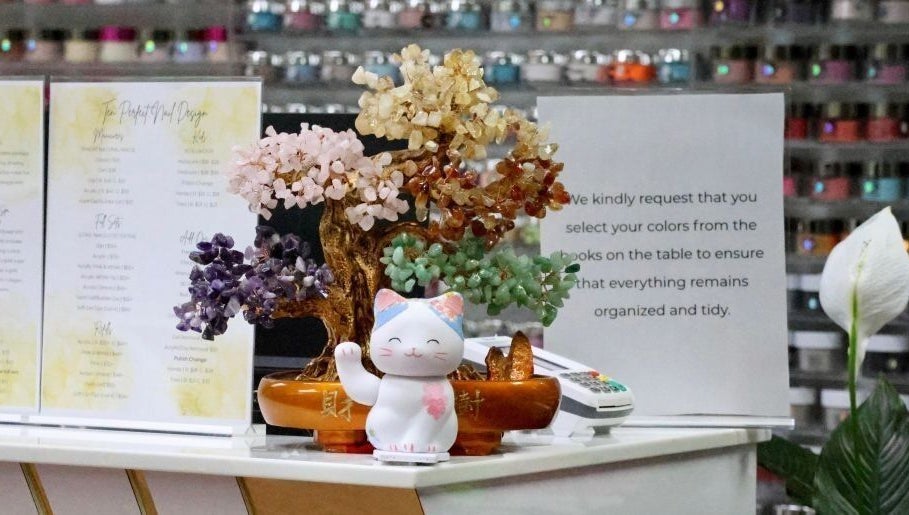 Charming decor at Ten Perfect Nail Design in Lowell, Massachusetts, US featuring a colorful gemstone tree and cat figurine.