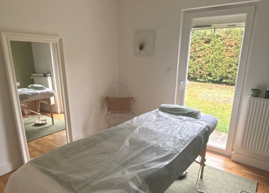 Salle de massage lumineuse à MaPhyto, Grande-Synthe, Hauts-de-France, FR avec table de soin et vue sur jardin.