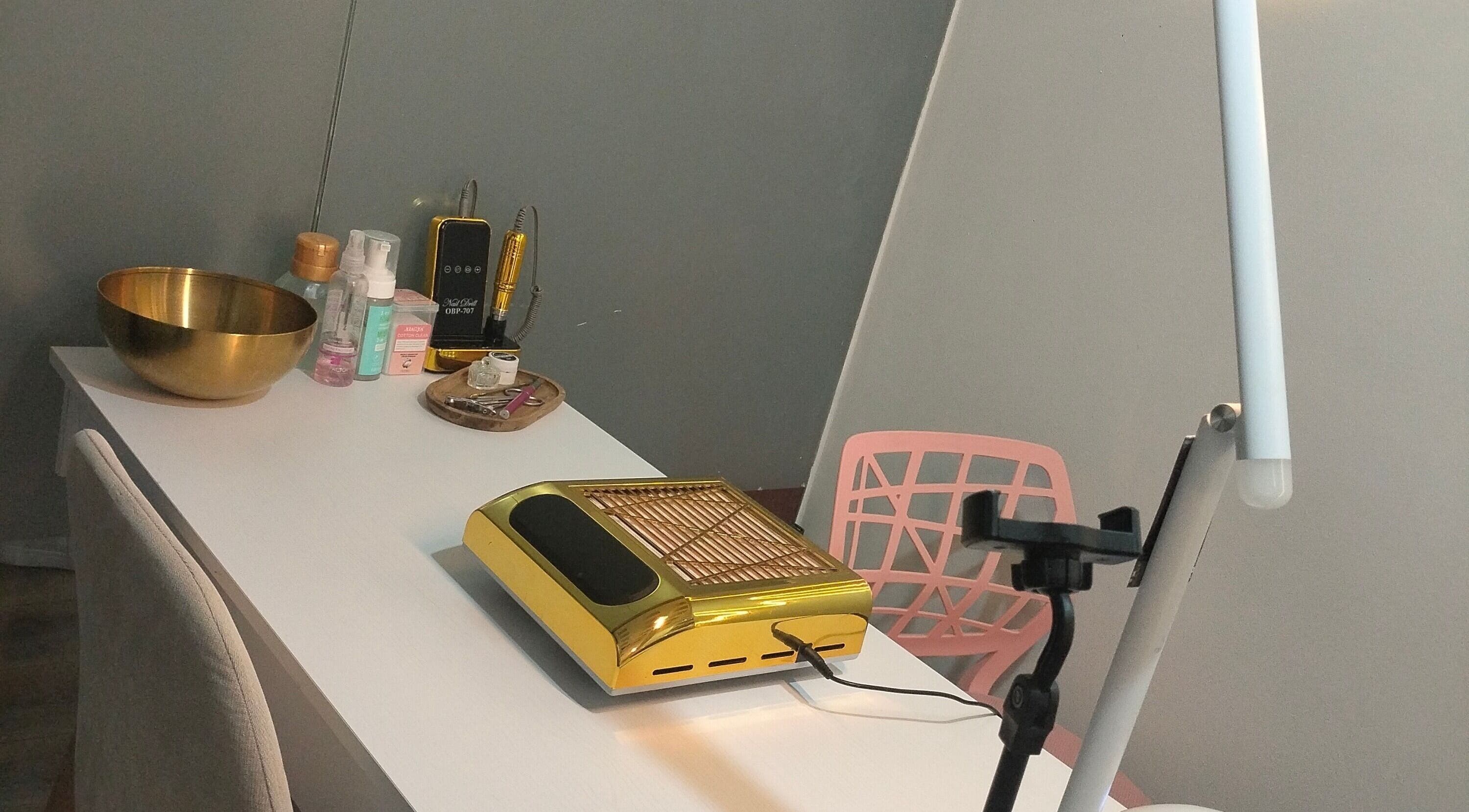 Mesa de trabajo en Jack Nailsmx, Ciudad De México, MX, con equipo dorado y productos de belleza.