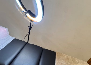 Luxurious treatment bed at The Beauty Spot, Jeddah, SA, with a glowing ring light for a relaxing experience.