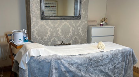Cozy treatment room at Homespa Nails & Beauty, Saint Columb, England showcasing a massage bed and elegant decor.
