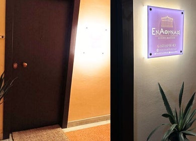 Είσοδος του En Athinais Massage στην Αθήνα, GR με φωτεινή επιγραφή και φυτά.