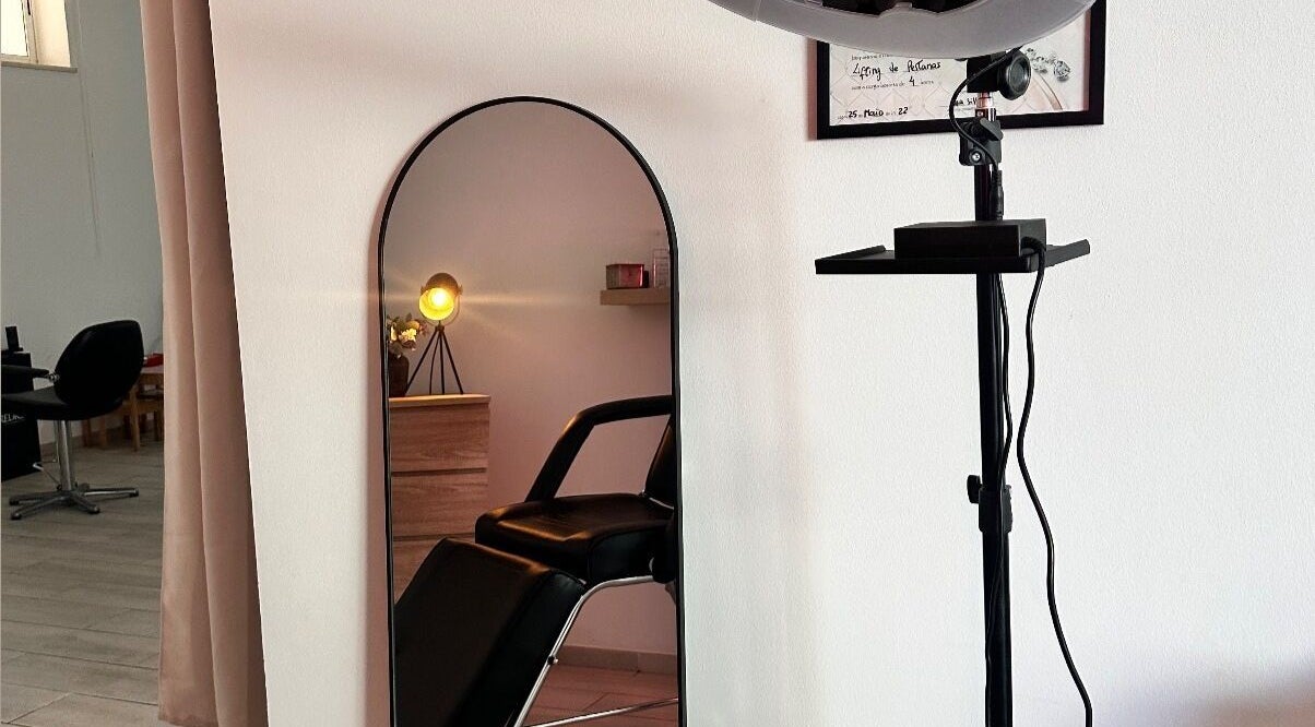 Espelho e cadeira no salão Femmi.Studio em Lagos, Faro, PT, destacando ambiente acolhedor e moderno.